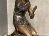 une statue en bronze représentant une femme assise sur un socle