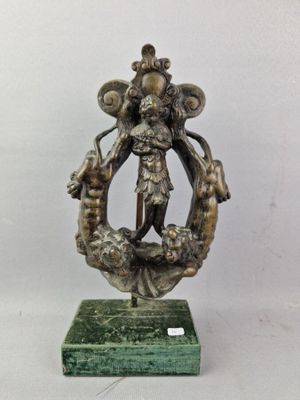 une statue en bronze représentant une femme tenant une couronne, posée sur un socle en marbre