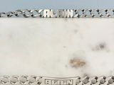 une assiette en argent sur laquelle figure un nom, posée sur une table