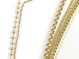 a gold necklace and bracelet set with pearls on a white background