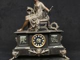une statue de femme assise au sommet d'une horloge
