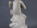 statue of an angel sitting on a rock on a gray background