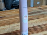 une brosse à dents électrique rose posée sur une table en bois