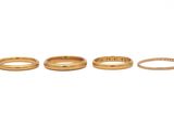 three gold wedding bands and a diamond ring on a white background