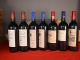six bottles of red wine are lined up on a table