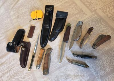 many different types of knives and knives laid out on a bed
