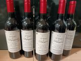 six bouteilles de vin rouge sont alignées sur une table