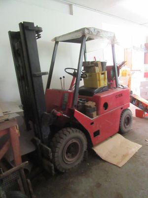 un chariot élévateur rouge dans un entrepôt, chargé de cartons