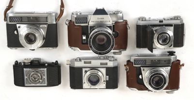several old cameras are lined up on a white surface