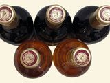 four bottles of wine are lined up in a row on a white surface