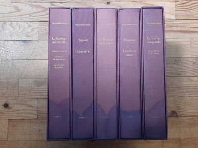 trois livres violets posés les uns à côté des autres sur une table en bois
