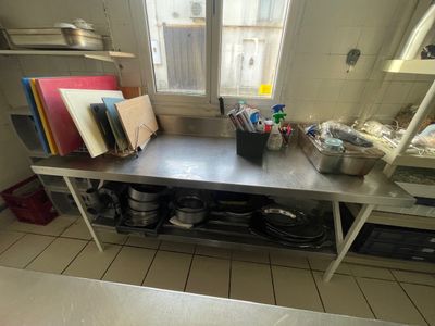 une cuisine avec un grand plan de travail en métal et une fenêtre