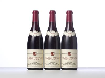 three bottles of red wine sit on a white surface