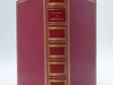 an old red book with gold trim sitting on top of a white surface