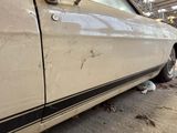 a dirty car parked in a garage next to a trash can