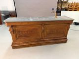 a wooden bar with a marble top in the middle of a room