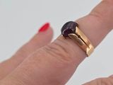 a woman ' s hand holding a ring with a black stone on it