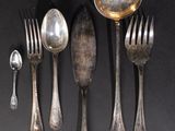 a lot of silver spoons and forks on a black table