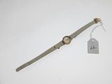 un gros plan d'une montre-bracelet posée sur une surface blanche, avec une étiquette de prix