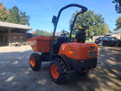 une photo d'un petit tracteur orange garé sur un parking