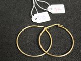 deux paires de boucles d'oreilles créoles en or posées sur une surface noire