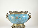 un vase bleu avec un socle doré sur fond blanc