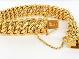 gros plan d'un bracelet en chaîne en or sur une surface blanche