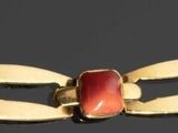 collier composé de perles dorées et de couleur corail sur fond noir