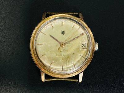 une montre-bracelet en or posée sur une surface noire