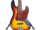 an electric bass guitar sitting on top of a stand on a white surface
