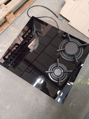 une cuisinière noire posée à même le sol, à côté d'une palette de bois