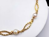 a close up of a gold chain bracelet with pearls on it