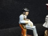 two figurines of a man and a woman sitting on a bench