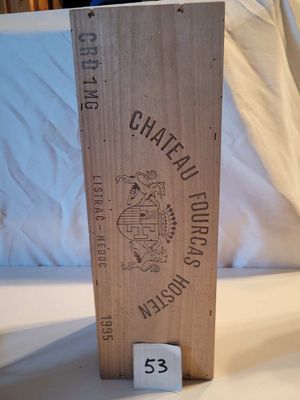 une boîte en bois sur laquelle est collée une étiquette, posée sur un lit