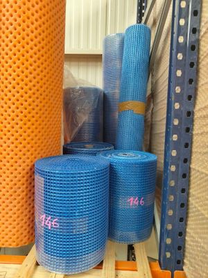 Plusieurs rouleaux de filet bleu et orange sont empilés sur une palette