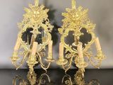 pair of gold plated wall sconces with candles and a mirror