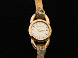 une montre-bracelet en or sertie de diamants, sur un fond noir