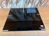 une plaque de cuisson en verre noir posée sur une table en bois