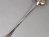 a silver spoon with a spoon handle on a gray surface