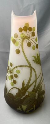 un vase blanc orné de motifs verts et marron
