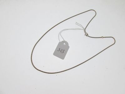 un collier en argent muni d'une plaque, posé sur une surface blanche