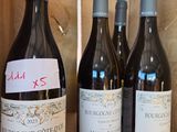 several bottles of wine are lined up on a wooden shelf