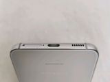 the back of a silver samsung phone sitting on top of a white surface