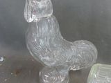 a glass chicken sitting on a table next to a glass container