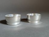 two silver cups sitting next to each other on a table