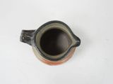 a brown and black cup sitting on a white table