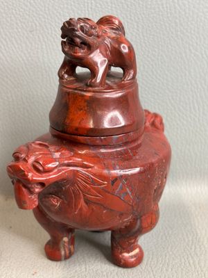 an image of a small red vase with a lion on top of it