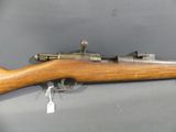 a close up of a rifle on display on a gray surface