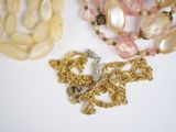two necklaces with pearls and a cross on a white surface