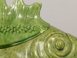 a green vase that has a fish on top of it